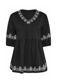 Tunic nera con scollo a V e maniche a tre quarti. Presenta ricami floreali bianchi lungo lo scollo e i polsini, con un orlo inferiore arr gathered.