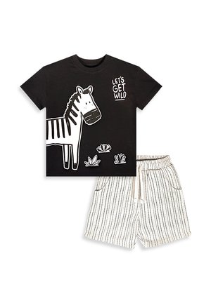 Czarny T-shirt z białą zebrą i napisem "LET'S GET WILD" zestawiony z białymi szortami z cienkimi czarnymi pionowymi paskami i ściągaczem w talii.