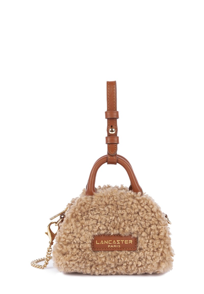 Borsa di colore tan con una texture morbida, accenti in pelle marrone, manico corto e hardware dorato. Presenta il logo su una patch in pelle.