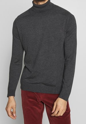 Donkergrijze coltrui van zachte stof, met lange mouwen, geribde hals en zoom, en een klassiek model. Corduroy broek zichtbaar.