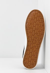 Semelle en toile classique, avec un motif de grip en caoutchouc brun texturé, une bordure blanche et un marquage de taille "37".