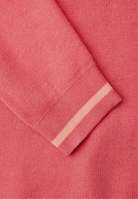 Gros plan sur la manche d'un pull en tricot rose avec un bord-côte comportant une seule rayure rose clair.