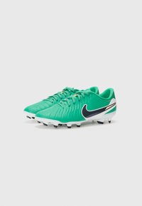 Green synthetic soccer cleats with textured upper, black Nike swoosh, white sole, and molded studs for traction on grass.