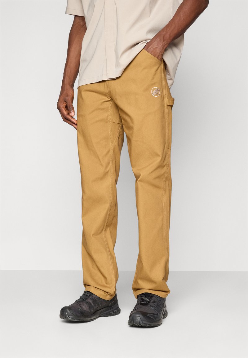 Pantalons cargo beiges avec une coupe décontractée, fabriqués en tissu durable. Dotés de poches latérales et d'un logo brodé sur le devant. Couture renforcée.