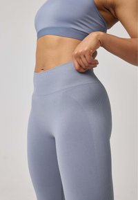 Sportiva di colore azzurro chiaro con leggings a vita alta e texture a coste. L'outfit presenta un design senza cuciture per garantire comfort durante l'attività.