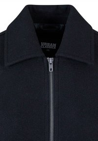 Must must have, klassikaline krae, sujuv tekstuur ja metallist tõmblukk. Silt ütleb "Urban Classics, XS."