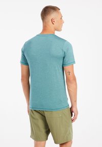 Teal T-shirt met korte mouwen van lichtgewicht stof, met een ronde hals en een gladde textuur, gecombineerd met olijfgroene shorts.