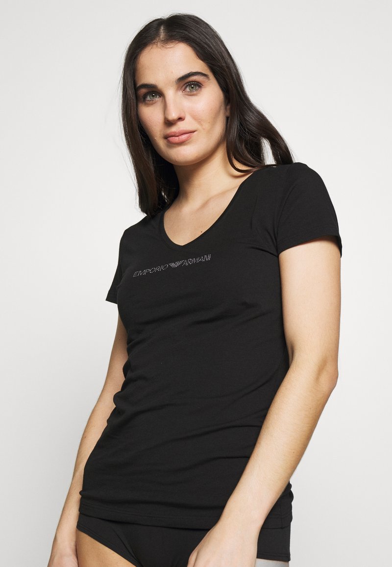 Camiseta de algodón negra de manga corta con escote en forma de V, que presenta un sutil texto decorativo en rhinestones a lo largo del pecho.