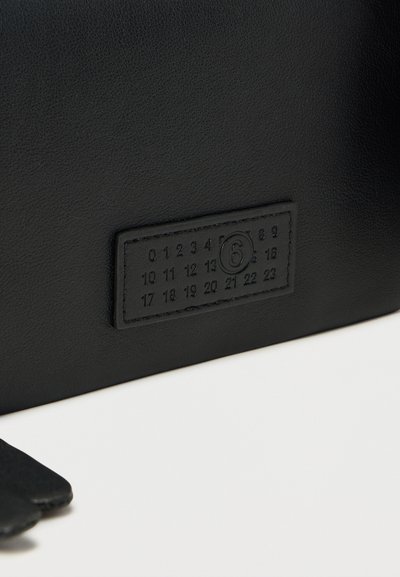 Μαύρο δερμάτινο αντικείμενο με ραμμένη ορθογώνια επιφάνεια που δείχνει αριθμούς 0-23, με τον αριθμό 6 κυκλωμένο στο κέντρο.