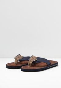 Sandale flip-flop bleumarin cu o curea din material texturat și accente de culoare maro deschis, având o branț căptușit și o talpă din cauciuc negru.