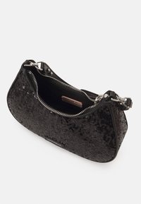 Svart paljetterad handväska med kurvad form, silverfärgad dragkedjestängning och kort axelrem. Inuti finns ett tygfoder.