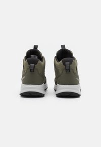 Zielone buty trekkingowe z teksturowaną górą, wypełnionym kołnierzem i czarnymi akcentami, z białą i czarną podeszwą, zaprojektowane do użytku na świeżym powietrzu.