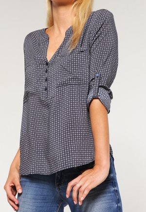 Blusa botton up blu navy con piccoli motivi circolari, scollatura a v e maniche arrotolate. Realizzata in tessuto leggero, vestibilità comoda.