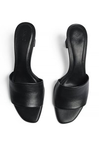 Par črnih sandala z odprto prstjo, brez zadrge, na peto, širokim usnjenim trakom in blok petami, prikazanih od zgoraj na belem ozadju.