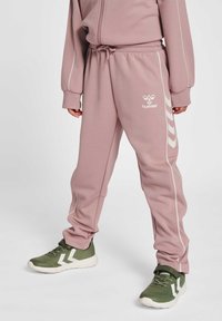 Rosa joggingsbyxor med vita sidostripes och logotyp. Tillverkade av mjukt tyg, med elastisk midja och justerbar dragsko för komfort.