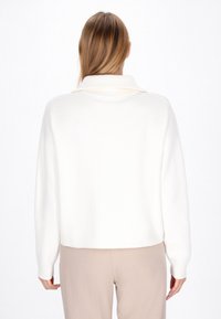 Hvid, chunky-strikket sweater med høj krave, cropped design og ribbede manchetter. Glat tekstur, minimalistisk stil, velegnet til lag-på-lag.