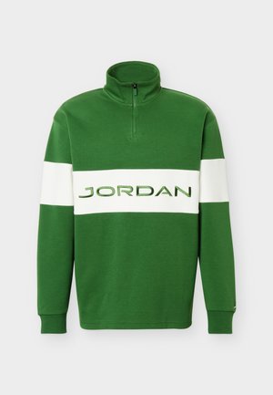 Sweat-shirt vert à fermeture quart de zip avec une bande horizontale blanche sur la poitrine arborant le mot "JORDAN" en lettres vertes.