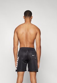 Svart idrettsshorts med elastisk midje, sidelomme og «NIKE»-logo i hvitt på venstre side. Glatt, lett materiale.