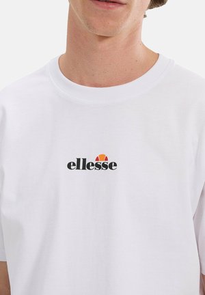 Male wearing white crew neck t-shirt with black and orange ellesse logo centered on the chest against a plain background.
