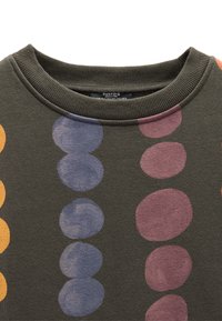 Ciemnozielona bluza z prążkowanym kołnierzem ozdobionym dużymi, wielokolorowymi kropkami w kolorach pomarańczowym, fioletowym i niebieskim. Miękka faktura, casualowy design.