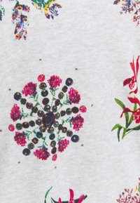 Motif textile floral avec des groupes circulaires de fleurs roses, des tiges vertes et des accents ronds foncés sur un tissu gris clair, orné de petits points dorés.