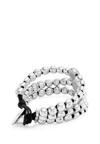 Pulsera de cuentas plateadas con tres hilos, que cuenta con un cordón elástico negro y un cierre metálico triangular para un ajuste seguro.