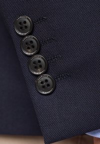 Granatowy, teksturowany materiał z czterema czarnymi guzikami na cztery dziurki, na każdym guziku wytłoczone logo marki "Lancerto".