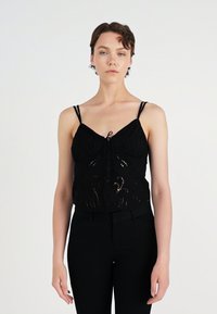 Svart cropped topp med spagettistropper, knapper foran og broderte detaljer. Gjennomsiktig tekstur med et mønstret design.