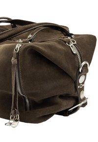 Brązowa zamszowa torba podróżna z srebrnymi zamkami błyskawicznymi, skórzanymi uchwytami i metalowymi detalami z klamrą na białym tle.