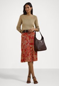 Strikket beige genser med strukturert yoke, blomstret rød skjørt, brun belte og brun skulderveske. Modellen har på seg mørke sandalene med stropper.