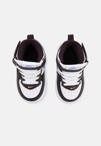 Sapatilhas Nike em preto e branco com detalhes em azul, exterior em pele, biqueira redonda, colarinho acolchoado, tira ajustável e sola de borracha texturizada.