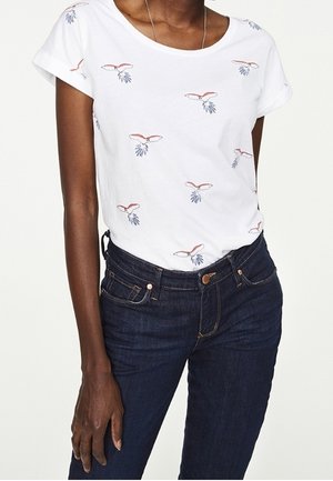 Hvid t-shirt med korte ærmer og blomsterprint i rød og blå, parret med mørkeblå denim jeans med en klassisk pasform.