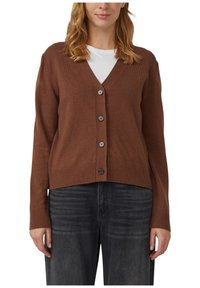 Brązowy kardigan na guziki z dekoltem w serek, z prążkowanymi mankietami i dołem. Wykonany z miękkiego materiału, z sześcioma czarnymi guzikami. Nosi się go na białą koszulę.