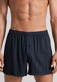 Marinblå vävda boxerkalsonger med elastisk midja, med en enkel knappstängning och subtila vertikala ränder.