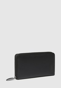 Portefeuille en cuir noir avec une finition texturée, forme rectangulaire, fermeture éclair et quincaillerie argentée ; doté d'une petite tirette de fermeture éclair allongée.