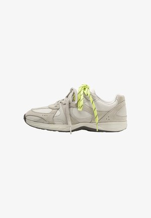 Pantof sport gri deschis văzut din lateral, cu accente bej și un șiret galben aprins legat alături de un șiret gri.