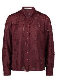 Blusa a maniche lunghe di un rosso scuro con tessuto frangiato testurizzato, chiusura con bottoni frontale e un piccolo colletto alla coreana.