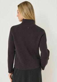 Pull en maille côtelée gris foncé avec un col haut et des manches longues. Présente un petit détail de bouton à l'arrière. Texture douce.