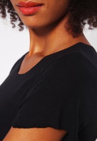 Czarny, teksturowany sweter o okrągłym dekolcie i krótkich rękawach, z delikatnym prążkowanym wzorem.