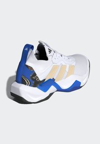 Scarpa sportiva bianca con strisce beige, supporto del tallone blu, motivo floreale nero e suola spessa su sfondo grigio chiaro.