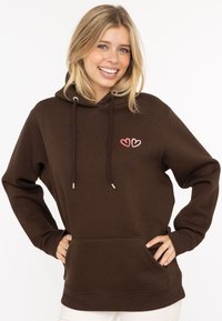 Brązowy hoodie z kieszenią kangurzą, sznurkami i różowym haftem serca. Posiada miękką teksturę i luźny krój.