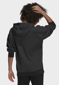 Szara bluza z kapturem wykonana z teksturowanej tkaniny, z prążkowanymi mankietami i pasem. Kaptur jest duży, a krój luźny.