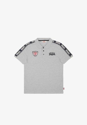 Vaaleanharmaa poolopaita mustilla napeilla, Lonsdale-logo rinnassa ja hihoissa sekä Britannian lipun merkki vasemmassa ylälaidassa.