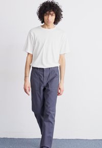 White short-sleeve t-shirt paired with dark navy wide-leg trousers, featuring front pockets. Smooth fabric, relaxed fit, minimalist design.