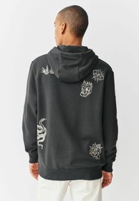 Donkergrijze hoodie met een trekkoordcapuchon, voorzien van witte geborduurde ontwerpen: vogels, vlammen, een slang en een roos op de achterkant.