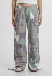 Baggy cargo pants in a pastel palette with diamond patterns. Made of fabric with pockets on the sides and a drawstring hem.
