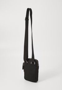 Borsa a tracolla nera in tessuto con forma rettangolare, cerniera argentata e tracolla regolabile. Texture liscia e design minimalista.