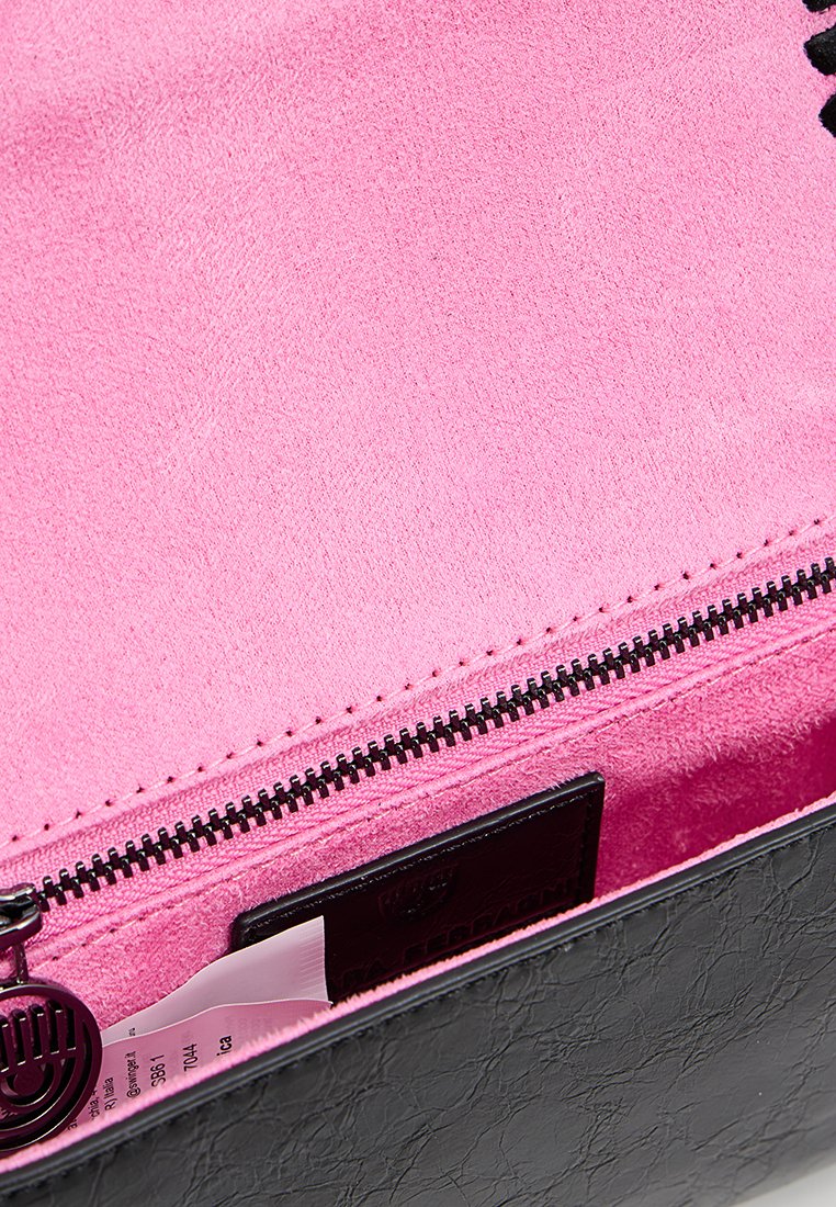 Intérieur de sac noir en synthétique avec une doublure rose lisse et vive. Comprend une fermeture éclair avec une fermeture noire et un petit accent en métal brillant.