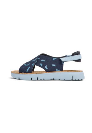 Modré sandály s vzorem a korkovou stélkou, s křížovými popruhy a světle modrou gumovou podrážkou. Nastavitelný pásek na patě zajišťuje bezpečné nošení.