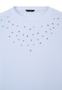 T-shirt bianca in cotone con scollo rotondo e borchie decorative argentate sparse sulla parte anteriore. Tessuto morbido con una finitura liscia.